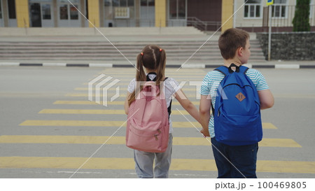 child students cross road zebra crossing. friends classmates pass car pedestrian crossing sign. give way child sign. boy girl with school backpacks run school by hand. brother sister child with city 100469805
