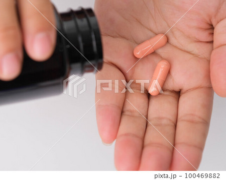 Close-up of woman pouring pills from bottle for medicinal purposes. Woman holding pills in hand with water. Healthcare, medicine, treatment, therapy concept 100469882