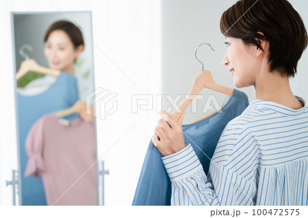 鏡の前で服選びをしている若い女性　ファッションイメージ 100472575