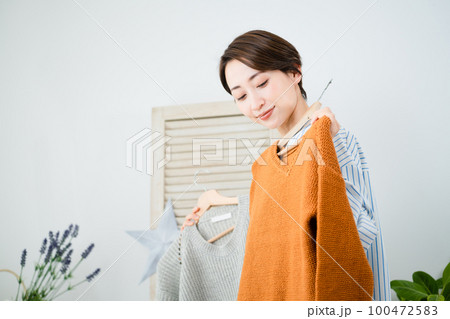 鏡の前で服選びをしている若い女性　ファッションイメージ 100472583