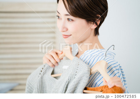 鏡の前で服選びをしている若い女性　ファッションイメージ 100472585
