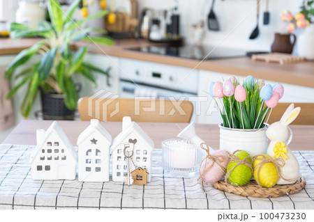 Key to house of cozy home with Easter decor with rabbit and eggs on table of kitchen. Building, design, project, moving to new house, mortgage, insurance, rent and purchase real estate Key to house of cozy home with Easter decor with rabbit and eggs on table of kitchen. Building, design, project, moving to new house, mortgage, insurance, rent and purchase real estate 100473230