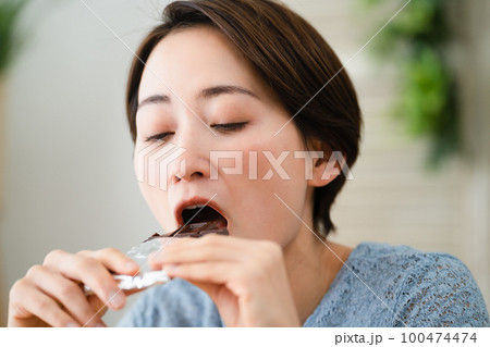 チョコレートを食べる若い女性　飲食イメージ	 100474474