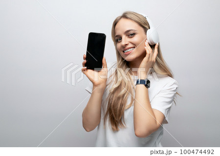 woman in wireless headphones with blank screen on phone on white background woman in wireless headphones with blank screen on phone on white background 100474492