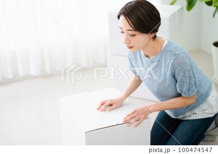 段ボールから荷物を取り出す若い女性　引っ越しイメージ 100474547