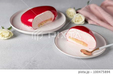 slice of mousse cake on white plate on gray background with white roses 100475894
