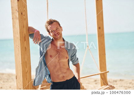 Shows body. Young european man have vacation and enjoying free time on the beach of sea Shows body. Young european man have vacation and enjoying free time on the beach of sea 100476300