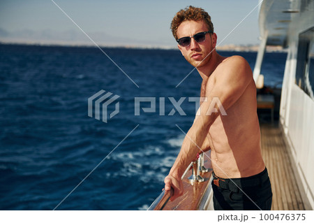 Warm weather. Young male tourist is on the yacht on the sea. Conception of vacation 100476375