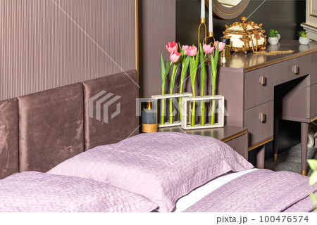 Fresh blooming red tulips in stylish vases from glass transparent test tubes on the background of the bedroom interior. Fresh blooming red tulips in stylish vases from glass transparent test tubes on the background of the bedroom interior. 100476574