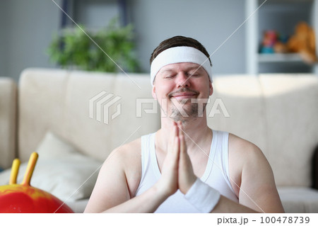 Handsome athletic young man presses hands to chest in namaste nirvana pose 100478739