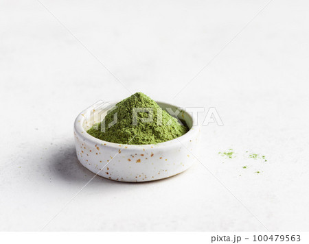 Green superfood powder in small bowl 100479563