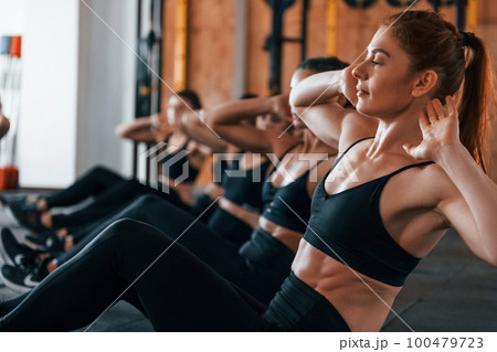 Doing abs. Group of young sportive people have crossfit day indoors in gym Doing abs. Group of young sportive people have crossfit day indoors in gym 100479723