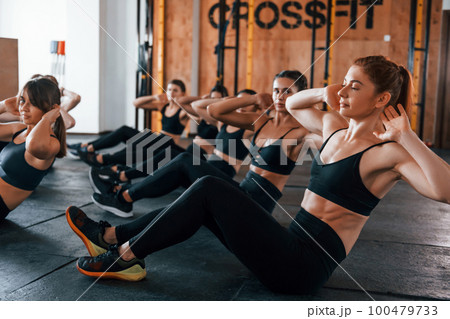 Doing abs. Group of young sportive people have crossfit day indoors in gym Doing abs. Group of young sportive people have crossfit day indoors in gym 100479733