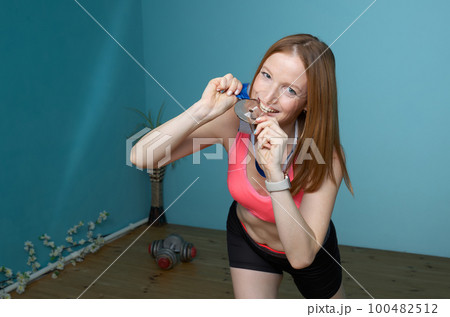 Woman in sportswear rejoices at a won sports medal Woman in sportswear rejoices at a won sports medal 100482512