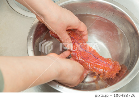 【イクラの醤油漬けを作るために、塩を入れたぬるま湯に生イクラを入れほぐす】 【イクラの醤油漬けを作るために、塩を入れたぬるま湯に生イクラを入れほぐす】 100483726