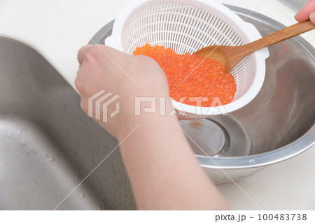 【イクラの醤油漬けを作るために、洗い終わった生イクラをスプーンでお酒を馴染ませる】 【イクラの醤油漬けを作るために、洗い終わった生イクラをスプーンでお酒を馴染ませる】 100483738