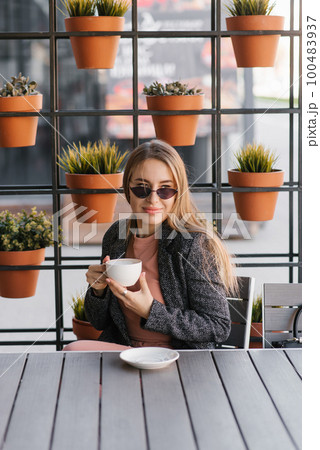 A beautiful pretty girl in a cafe drinking coffee on a summer terrace A beautiful pretty girl in a cafe drinking coffee on a summer terrace 100483937