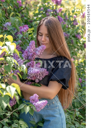 portrait of young woman with long hair outdoors in blooming lilac garden portrait of young woman with long hair outdoors in blooming lilac garden 100484544