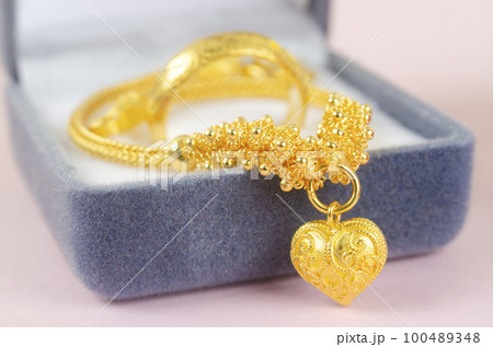 The Gold necklace and heart shape pendant with ring on blue velvet box. 100489348