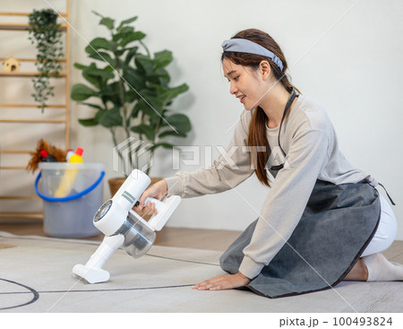 Housekeeper is using cordless vacuum cleaner with handheld for cleanups and vacuuming dirt on carpet Housekeeper is using cordless vacuum cleaner with handheld for cleanups and vacuuming dirt on carpet 100493824