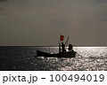 Silhouettes of Asian fishermen. Driving a traditional boat in the sea as the sun sets 100494019
