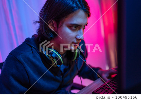 Handsome boy playing E-Sport game or streamer, Enjoying playing online games, Entertainment  or technology game trends, Live show play games, Focus monitor, Blue and red lights 100495166