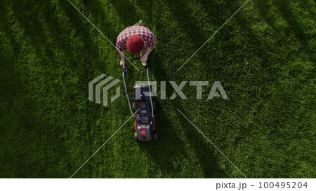 Professional worker with lawn mower mows the grass, top view. Copy space Professional worker with lawn mower mows the grass, top view. Copy space 100495204