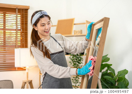 Housekeeper is wearing protective gloves and using microfiber cloth to cleanups and wiping dirt on the glass Housekeeper is wearing protective gloves and using microfiber cloth to cleanups and wiping dirt on the glass 100495497