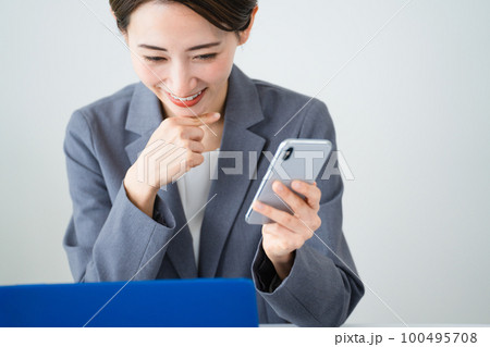 ノートパソコンとスマートフォンを使う若い女性　ビジネスイメージ 100495708