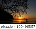 Man playing somersaults on the beach at sunset, red sky 100496357