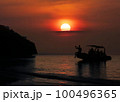 A group of Asian men are sitting on a boat looking at the sunset, the beautiful red sky. Right in front of the beach 100496365