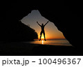 Man jumping on the beach at sunset, beautiful red sky 100496367