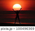 Man jumping on the beach at sunset, beautiful red sky 100496369