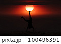 Man playing somersaults on the beach at sunset, red sky 100496391