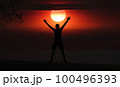 Man jumping on the beach at sunset, beautiful red sky 100496393