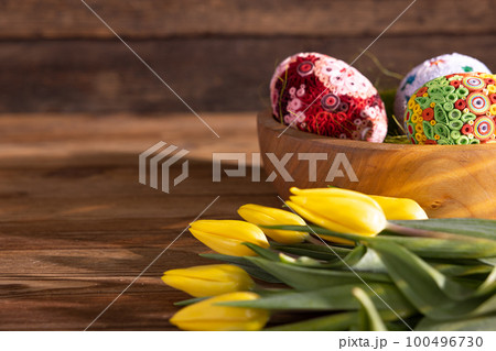 Side view of a bowl with large colorful Easter eggs on a background of boards. 100496730