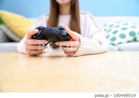 リビングでゲームする女性　ゲーム女子　ゲームコントローラー　休日　ライフスタイル　顔無し　 100499019