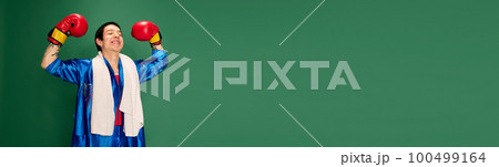 Portrait of young man, boxer in uniform posing after win isolated over green background. Concept of victory, sport, competition, training, energy. Portrait of young man, boxer in uniform posing after win isolated over green background. Concept of victory, sport, competition, training, energy. 100499164