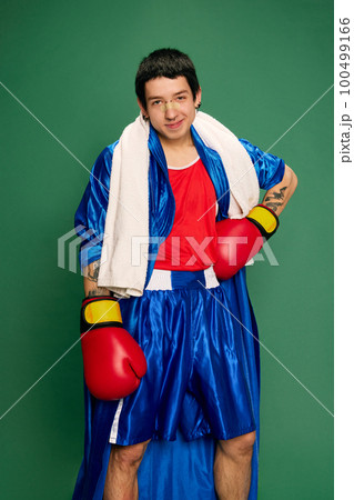 Funny portrait of beginner boxer in robe and shorts posing after fight isolated over green background. Sport, funny meme emotions, male hobbies 100499166