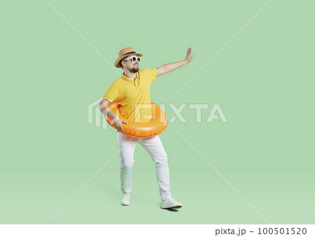 Funny man who is going on summer holiday is wearing inflatable ring, dancing and waving goodbye 100501520