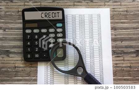 Credit. The word CREDIT is written on the display of a calculator near documents with a magnifying Credit. The word CREDIT is written on the display of a calculator near documents with a magnifying 100503583