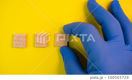 Hand in blue gloves point on clean wooden blocks on colored yellow background. Medical scientific or biological theme. Template for text or concept. Advertising mock up. Presentation flat lay mock up 100503729