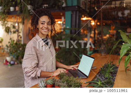 Successful female florist working laptop in own floral studio, check customers order  100511961