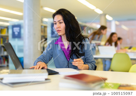 Asian student woman in the library studying on a laptop Asian student woman in the library studying on a laptop 100515097