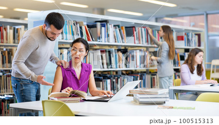Man helping woman to prepare for exams in library Man helping woman to prepare for exams in library 100515313