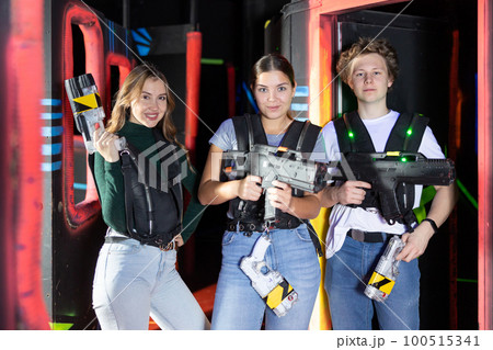 People posing with laser guns having fun on dark lasertag arena 100515341