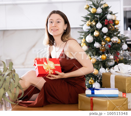 Woman poses with Christmas presents at home 100515348