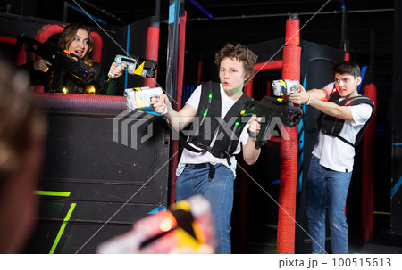 Laughing players mens and womens playing in teams in dark laser tag station 100515613