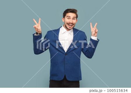 Delighted man with mustache standing ,with v signs, looking at camera with positive facial expression, wearing white shirt and jacket. Indoor studio shot isolated on light blue background. Delighted man with mustache standing ,with v signs, looking at camera with positive facial expression, wearing white shirt and jacket. Indoor studio shot isolated on light blue background. 100515634