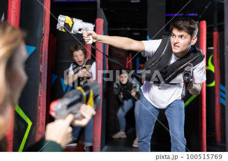 Excited teenager having fun playing lasertag in arena 100515769